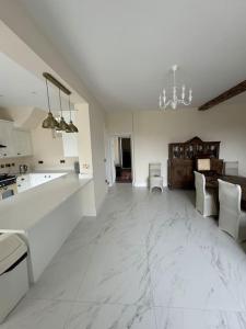 eine große weiße Küche mit weißen Böden und ein Esszimmer in der Unterkunft Cae Nest Hall in Llanbedr
