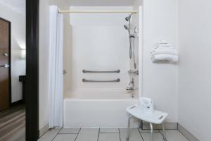 un bagno bianco con vasca e lavandino di Super 8 by Wyndham Grapevine/DFW Airport Northwest a Grapevine