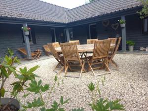 a wooden table and chairs in front of a house at Gite de la Chapelle option SPA in Verchocq