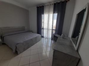 a bedroom with a bed and a large window at Elezi House in Durrës