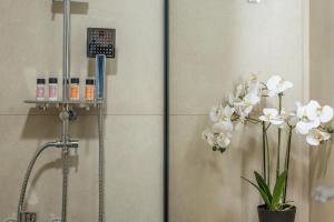 a shower with white flowers in a bathroom at Faflagos Apartments in Psari Forada +132 photos