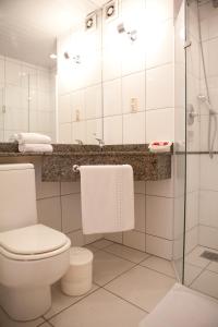 a bathroom with a toilet and a glass shower at Atalaia Palace Hotel in Guarapuava