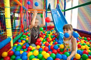 two young children playing in an indoor ball park at Świętokrzyska Polana - Medical Resort in Chrusty