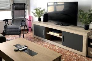 Una sala de estar con un televisor de pantalla plana en un centro de entretenimiento. en Manda Pola, en Santa Pola