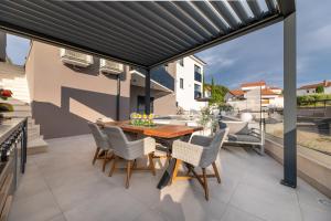a patio with a wooden table and chairs at Villa Aurea Apartments de Luxe Malinska Luxus Apartments mit beheiztem Pool Insel Krk in Malinska