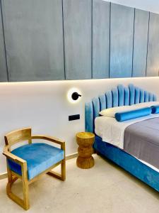 a bedroom with a blue bed and a chair at Tramonto Maisonettes & Suites in Parga