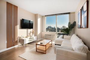 霍博肯Freedom Tower View -Amenity Packed with Pool -minutes to NYC的客厅里有一张白色的沙发和一扇大窗户
