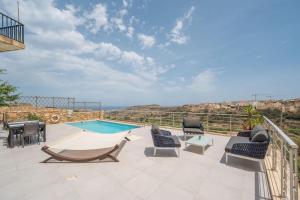 a patio with chairs and a swimming pool at Clifftop Lodge in Tal-Barmil