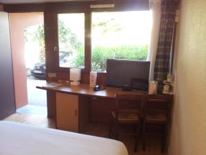 a bedroom with a desk with a computer and a window at Campanile Perpignan Sud in Perpignan