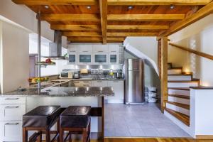 a kitchen with wooden ceilings and a counter with stools at Alexandra Pool Villa - Comfort & Views Near Town in Skopelos Town