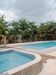 a large swimming pool with blue water and trees at Casa De Mira in Angeles