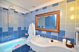 a bathroom with a tub, sink, mirror and bathtub at Tamarix Del Mar Suites in Kamari