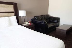 ein Hotelzimmer mit einem Bett und einem Ledersessel in der Unterkunft Days Inn by Wyndham Sudbury & Conference Centre in Sudbury