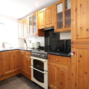 eine Küche mit Holzschränken und einem Herd mit Backofen in der Unterkunft Cnocachanach Cottage in Tarbert