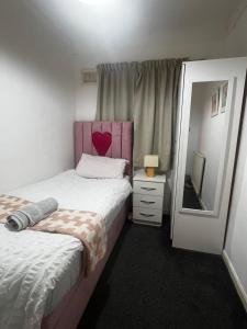 BS Lodge في ميتشام: غرفة نوم بسريرين مع اللوح الأمامي وردي ومرآة