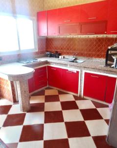 eine Küche mit roten Schränken und einem karierten Boden in der Unterkunft Villa Serene Oasis in Aït Ali