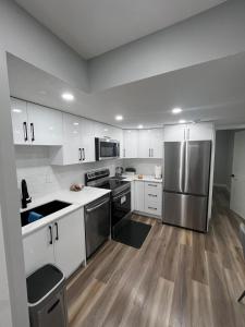 a kitchen with white cabinets and a stainless steel refrigerator at Adorable Private Suite in Seton SE, Calgary in Calgary