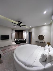 sypialnia z dużym białym łóżkiem i wentylatorem sufitowym w obiekcie The Luxus Lodge w mieście Islamabad