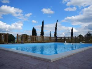 a large swimming pool with a fence and trees at Agriturismo Scaforno Vacanze in Castelnuovo della Misericordia