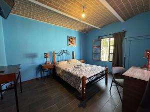 a bedroom with blue walls and a bed and a desk at Vista Reforma in Guanajuato