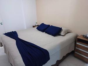 a bedroom with a bed with blue pillows on it at Apto frente mar maravilhoso centro mongaguá in Mongaguá