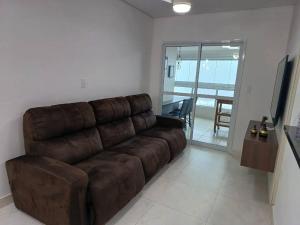 a brown leather couch in a living room with a table at Apto frente mar maravilhoso centro mongaguá in Mongaguá