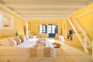 a bedroom with a large white bed and a staircase at Tamarix Del Mar Suites in Kamari