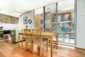 キャンベラにあるModern Two-Story City Pad With Pool, Gym & Saunaの木製のテーブルと椅子のあるキッチンとダイニングルーム
