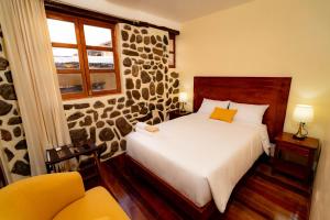 a bedroom with a bed and a stone wall at NUNA SUMAQ Hotel in Ollantaytambo