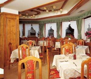 a dining room with tables and chairs with white table cloth at Hotel PORDOI in Arabba