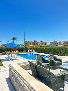 a swimming pool with chairs and an umbrella at فيلا للإيجار برايفت بول مارينا 5 الساحل الشمالي فيلا 5 غرف نوم مكيف بالكمال فرش فندقي in El Alamein