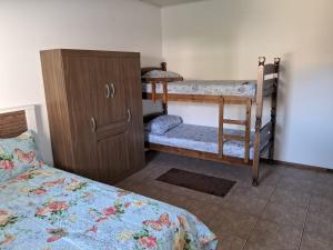 カンポス・ド・ジョルドンにあるApartamento Kit 04, em Campos do Jordãoのベッドルーム1室(二段ベッド2台、キャビネット付)