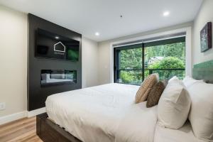 a bedroom with a large white bed and a window at Powderhorn 205 by Outpost Whistler in Whistler