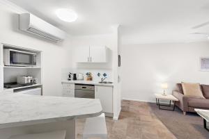 una cucina bianca con tavolo e divano di Upstairs 1 Bedroom Unit in Noosaville Resort a Noosaville
