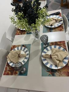 a white table with plates and a vase of flowers at Life Flats Temporada com Bela vista à 50m da Praia in Recife