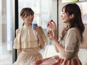 two women are talking and eating food together at Hotel Gracery Sapporo in Sapporo