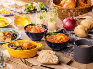 a wooden table topped with bowls of food and bread at Hotel Gracery Sapporo in Sapporo