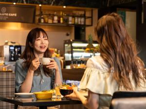 two women sitting at a table drinking coffee at Hotel Gracery Sapporo in Sapporo