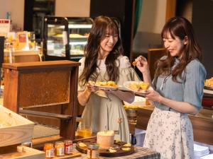 two women are holding plates of food at Hotel Gracery Sapporo in Sapporo