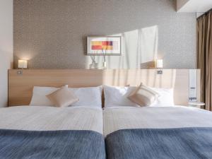 a bedroom with a large bed with white pillows at Hotel Gracery Sapporo in Sapporo