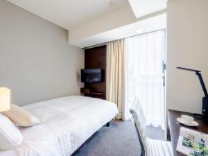 a hotel room with a bed and a window at Hotel Gracery Sapporo in Sapporo