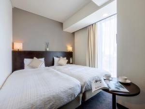 a bedroom with a bed with a table and a window at Hotel Gracery Sapporo in Sapporo