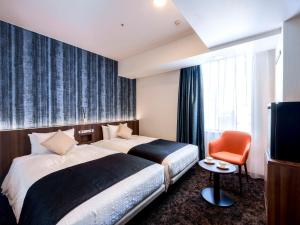 a hotel room with two beds and a television at Hotel Gracery Sapporo in Sapporo