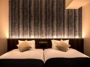 a bed with two pillows in front of a wall at Hotel Gracery Sapporo in Sapporo