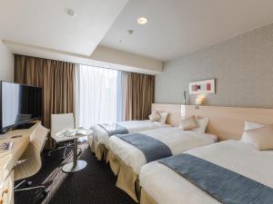 a hotel room with two beds and a flat screen tv at Hotel Gracery Sapporo in Sapporo