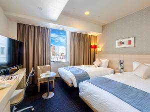 a hotel room with two beds and a television at Hotel Gracery Sapporo in Sapporo