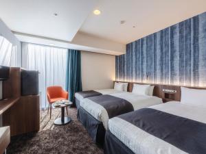 a hotel room with two beds and a television at Hotel Gracery Sapporo in Sapporo