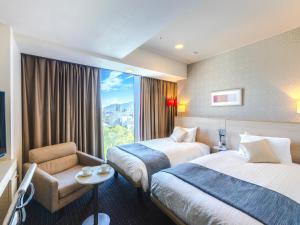 a hotel room with two beds and a window at Hotel Gracery Sapporo in Sapporo