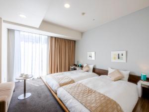 a bedroom with two beds and a window at Hotel Gracery Sapporo in Sapporo
