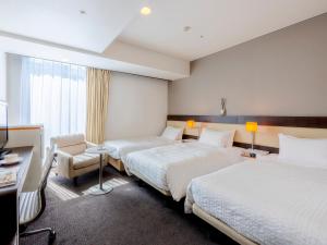 a hotel room with two beds and a chair at Hotel Gracery Sapporo in Sapporo